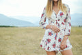 Woman in a white and red floral print dress standing on a farm — placeholder image