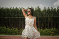 Woman in a relaxed white top holding her hair back, casual daytime style — placeholder image