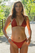 Woman in orange resort-style bikini standing on a beach, wide-leg resort wear reference — placeholder image