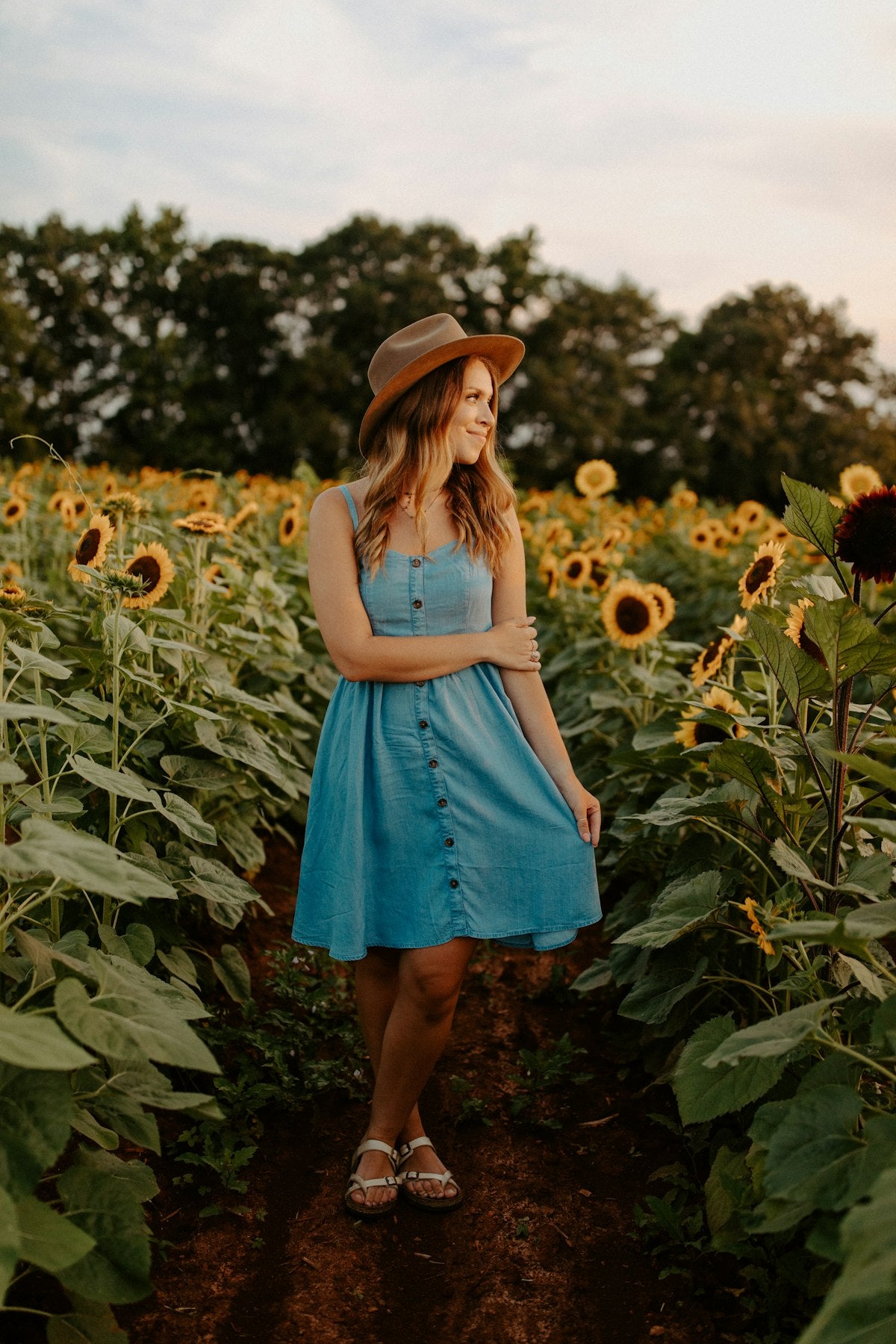 Woman in a fitted blue mini dress standing in a green grass field — placeholder image